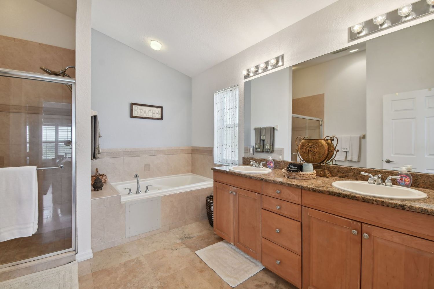 Primary bathroom with a jetted tub, double vanity and separate glass shower